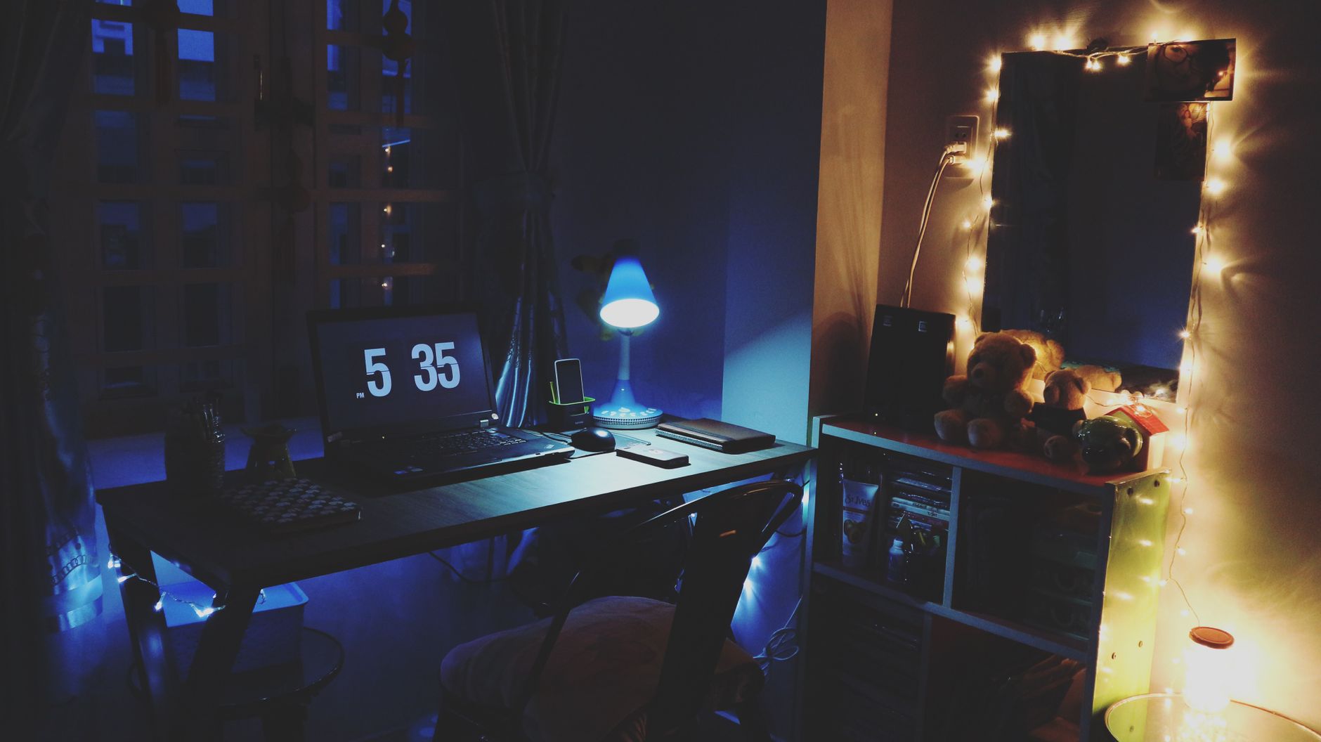 Varmt upplyst skrivbord kvällstid med laptop och ljusslinga, en typisk arbetsplats för distansuppdrag.